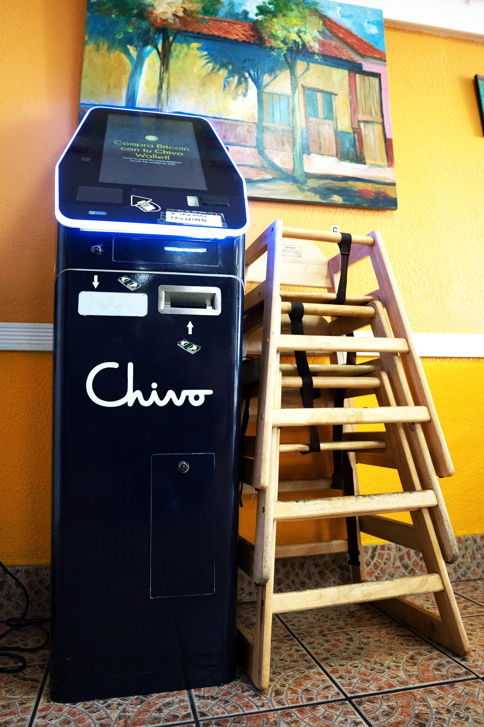 Chivo Bitcoin ATM next to a stack of wooden booster seats inside a Salvadoran restaurant in Oakland CA