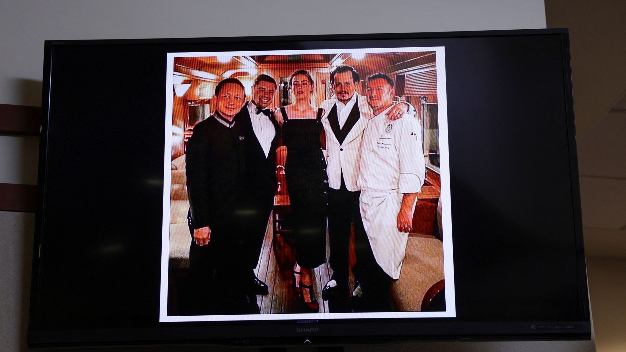  Picture introduced into evidence of Depp and Heard with the staff of the Orient Express train taken at the end of their honeymoon trip in Singapore after their wedding in 2015, is seen on the screen during Depp&#39;s defamation trial a