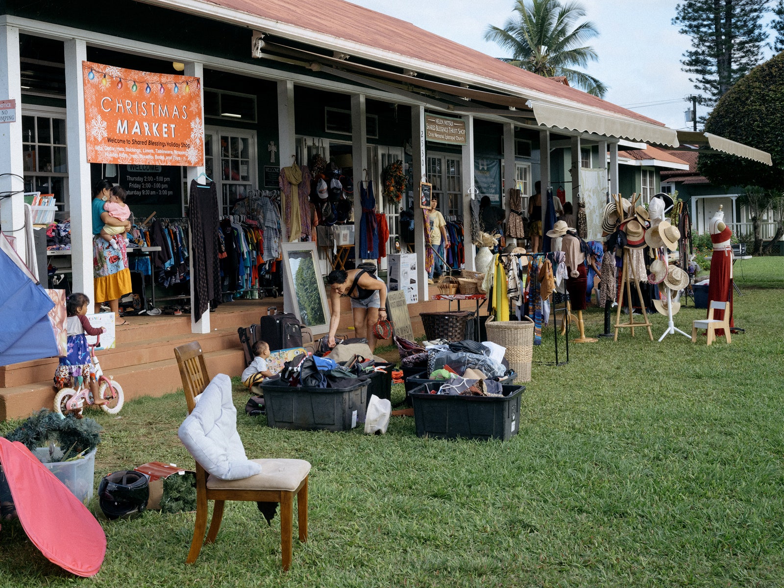 People shop at a Christmas market with various items displayed out front