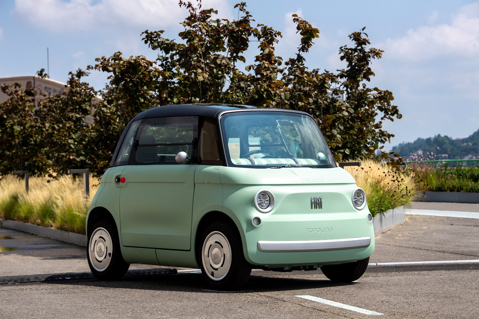 Small mint green car in an outdoor parking lot on a sunny day