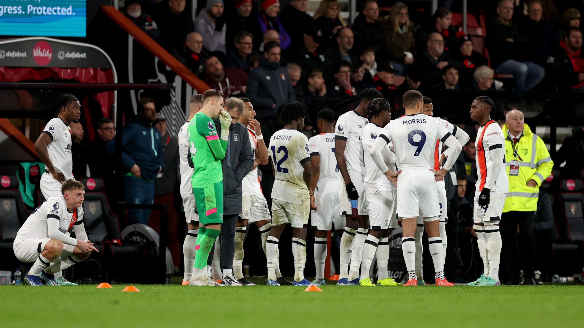 Luton Town&#39;s players wait on the sideline as team-mate Tom Lockyer (not pictured) receives treatment after collapsing on the pitch