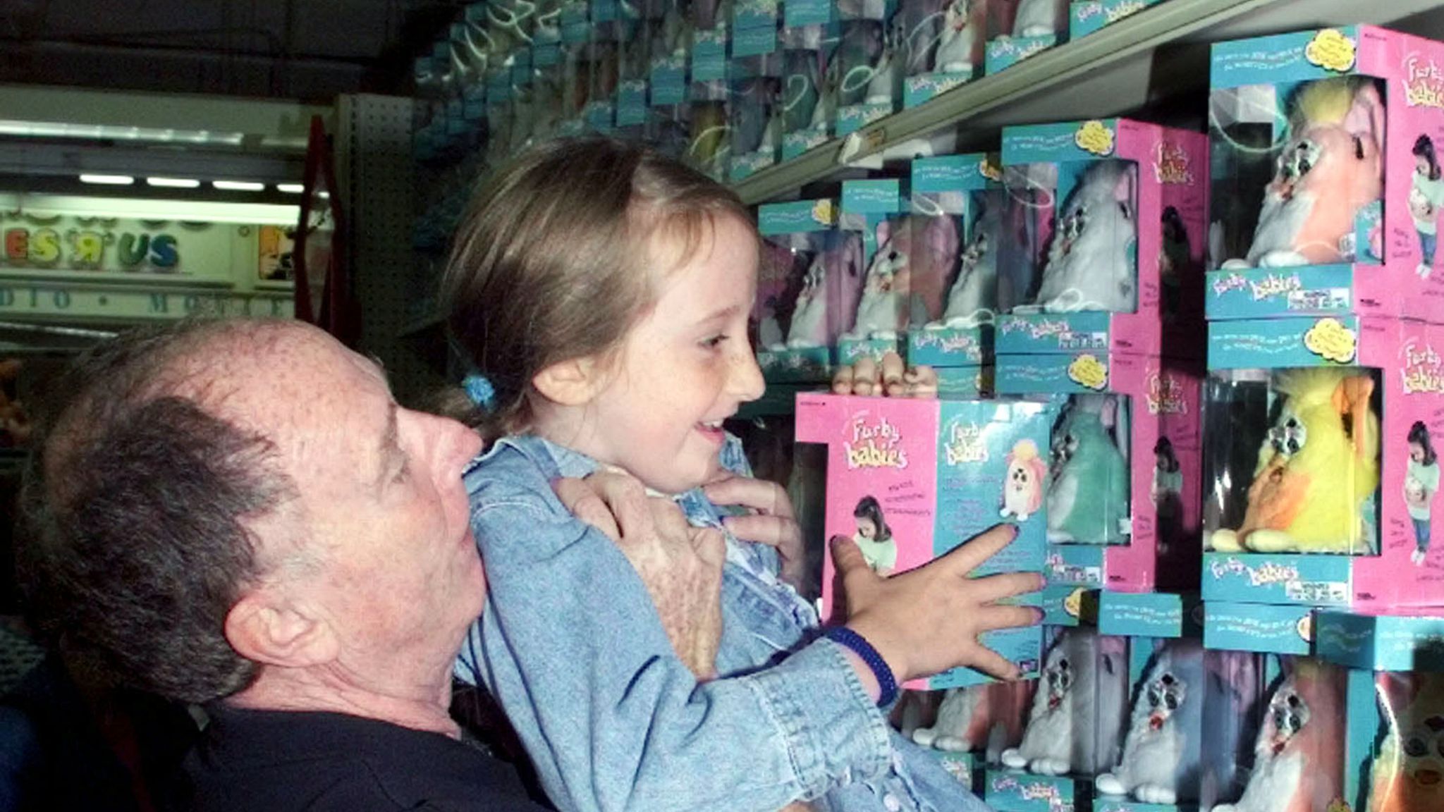 Rhyder McClure lowers his happy daughter Alexandra, 8, after lifting her to the top shelf to reach the Furby Baby toy she wanted at the Herald Square Toys "R" US store August 31 in New York. The two were among the first in line for the first sales of the new Tiger Electronics toy unveiled for sales for the first time. The smaller version of the successful Furby toy has a 25% increase in vocabulary and "learns" english faster than the original.