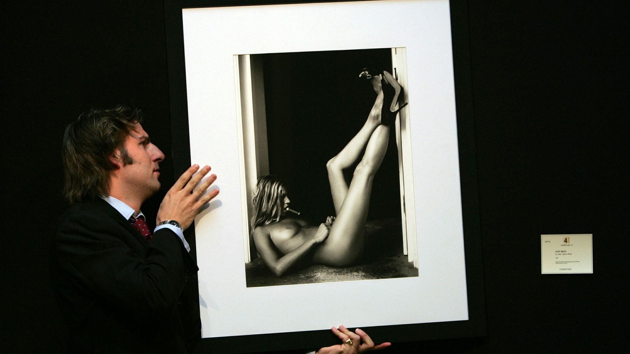 A man hangs a portrait of Kate Moss by artist Sam Taylor Wood at Christie&#39;s auction house in London in May 2005. President and founder of Jimmy Choo shoes, Tamara Mellon, unveiled a series of nude portraits of women including Kate Moss and Victoria Beckham wearing nothing but Jimmy Choo shoes and Cartier jewellery, to raise money for the Elton John Aids Foundation