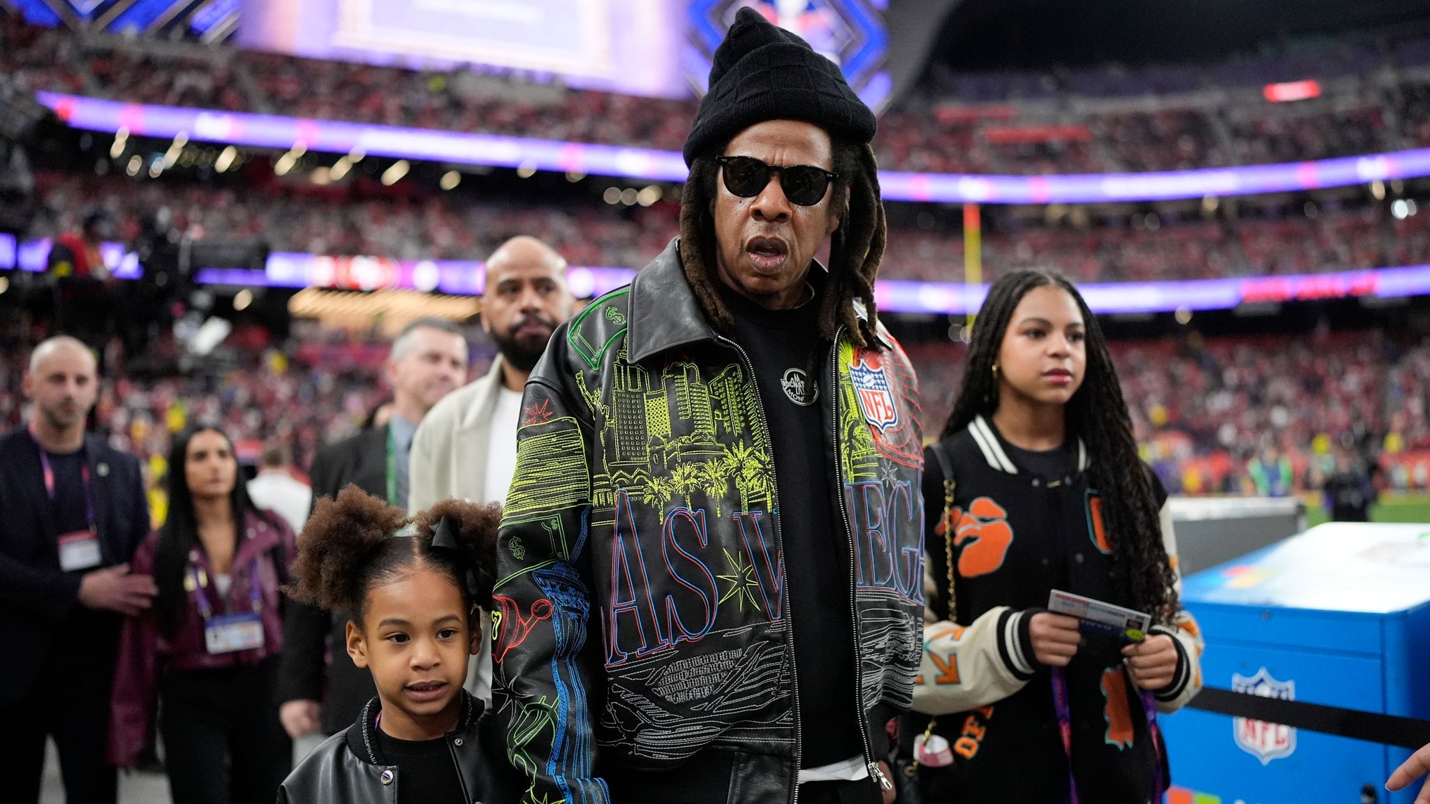 Rumi Carter, from left, Jay-Z, Blue Ivy Carter walks on the sidelines before the NFL Super Bowl 58 football game between the San Francisco 49ers and the Kansas City Chiefs, Sunday, Feb. 11, 2024, in Las Vegas. (AP Photo/George Walker IV)