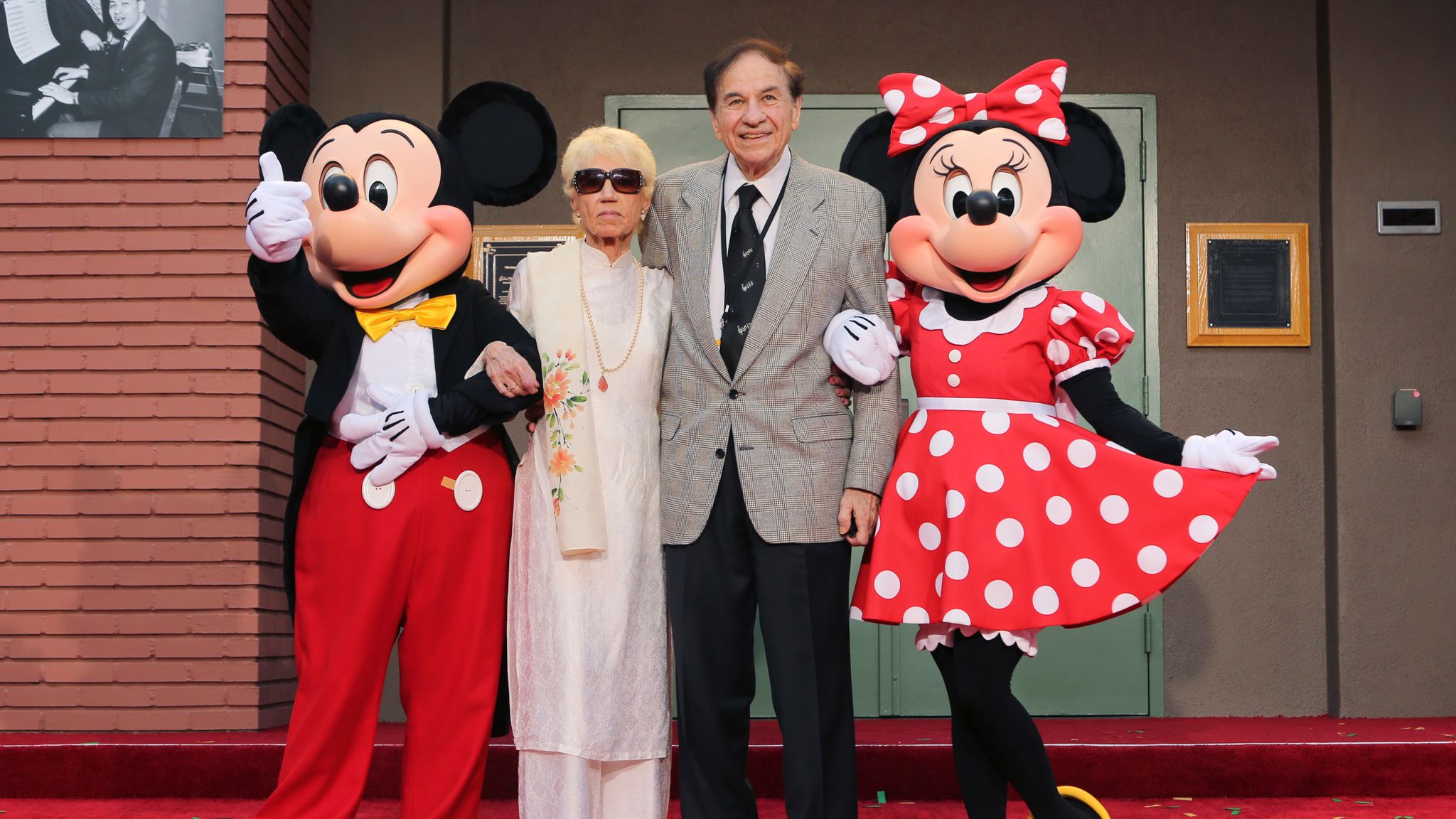 FILE - Mickey Mouse, from left, Elizabeth Gluck, Richard M. Sherman and Minnie Mouse pose for a photo at the ceremony honoring the Sherman Brothers with the rename of Disney Studios Soundstage A at the world premiere of Disney&#39;s "Christopher Robin" at the Walt Disney Studios, July 30, 2018, in Burbank, Calif. Sherman, one half of the prolific, award-winning pair of brothers who helped form millions of childhoods by penning classic Disney tunes, died Saturday, May 25, 2024. He was 95. (Photo by Willy Sanjuan/Invision/AP, File)