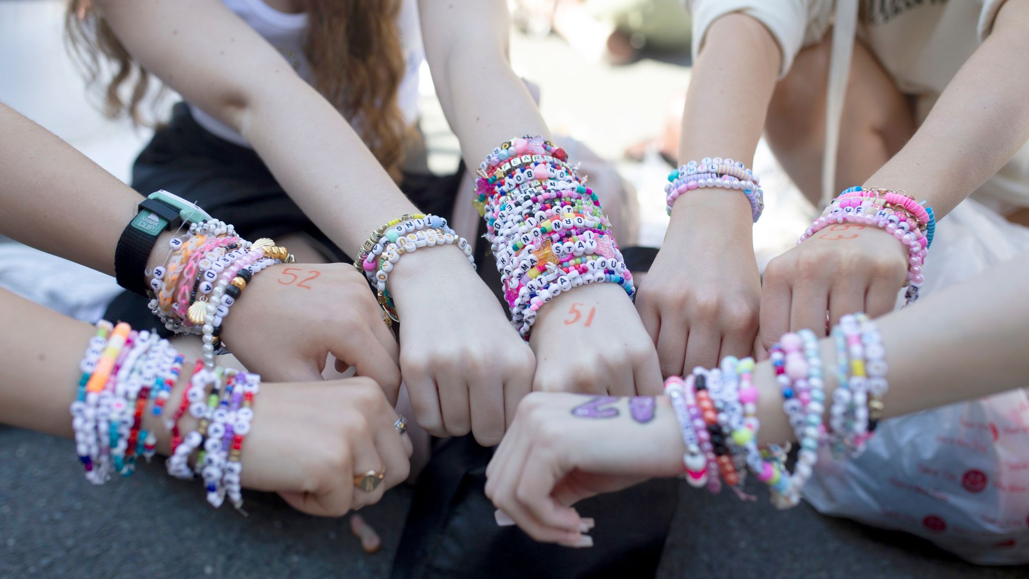 Fans display their bracelets as they wait to enter Wembley Stadium in London, ahead of Taylor Swift's first London concert, during her Eras Tour. Pic: PA