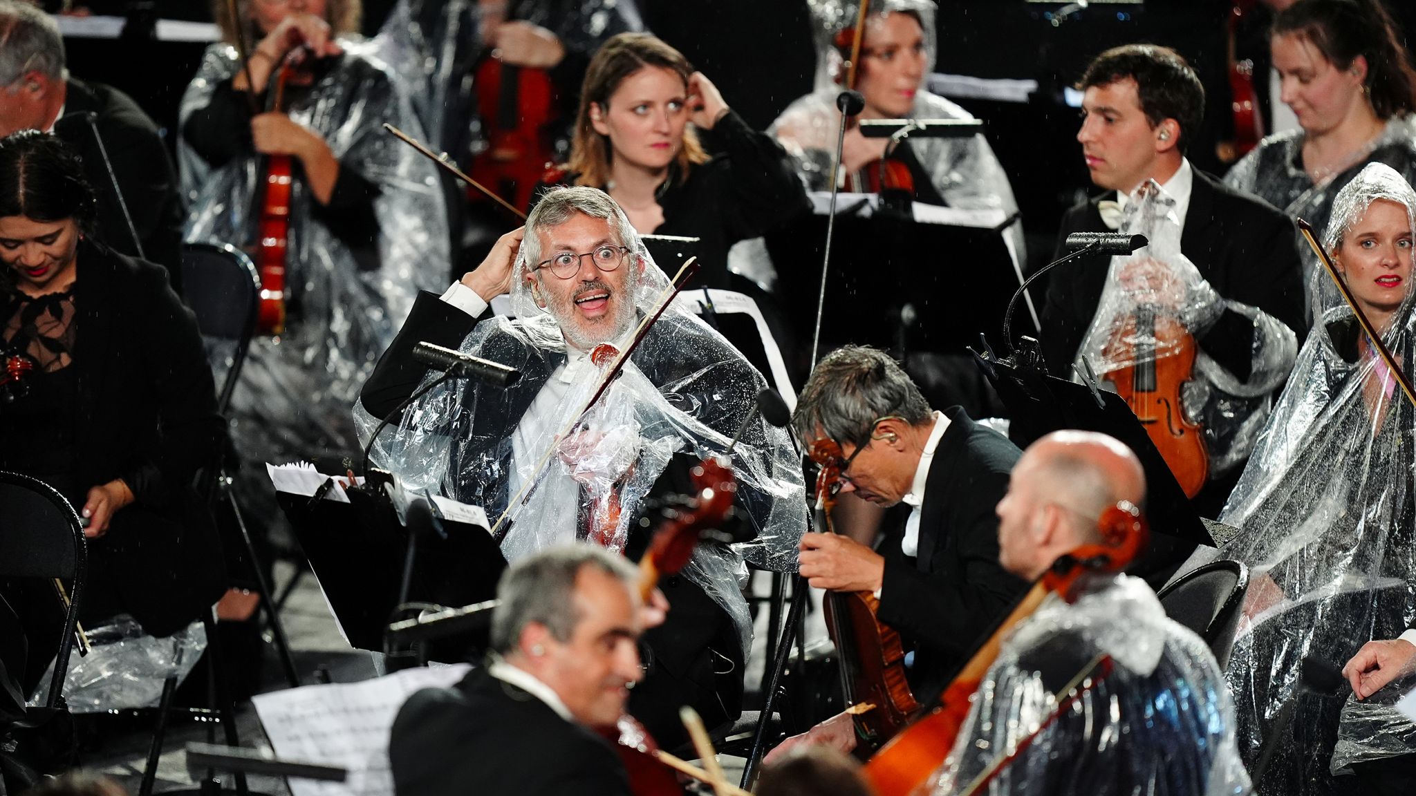 Musicians from the French National Orchestra shelter from the rain during the opening ceremony. Pic:PA