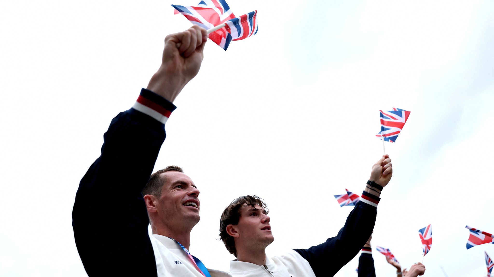 Tennis players Andy Murray and Jack Draper of Britain wave flags on the team boat 