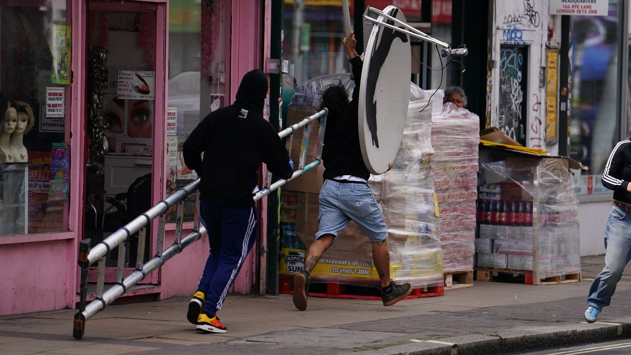 People remove a new artwork by Banksy, depicting a howling wolf painted on a satellite dish that was placed on a shop roof in Peckham, south London. The artist's latest artwork comes a day after he unveiled three monkeys painted on a bridge in Brick Lane, east London. Picture date: Thursday August 8, 2024. 