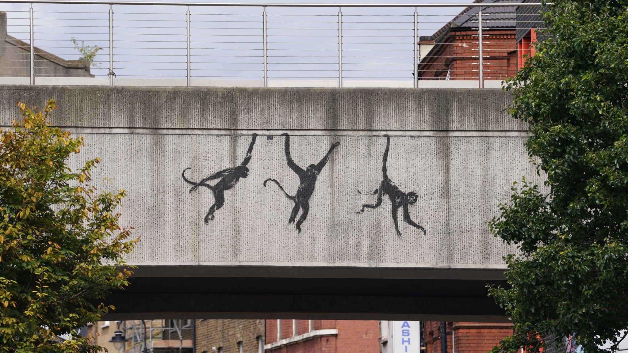 A new artwork depicting three monkeys unveiled by Banksy, painted on a bridge in Brick Lane. Pic: PA