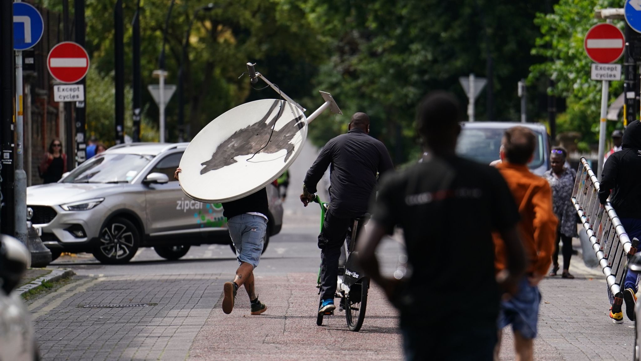 People remove a new artwork by Banksy, depicting a howling wolf painted on a satellite dish that was placed on a shop roof in Peckham, south London. The artist's latest artwork comes a day after he unveiled three monkeys painted on a bridge in Brick Lane, east London. Picture date: Thursday August 8, 2024. 