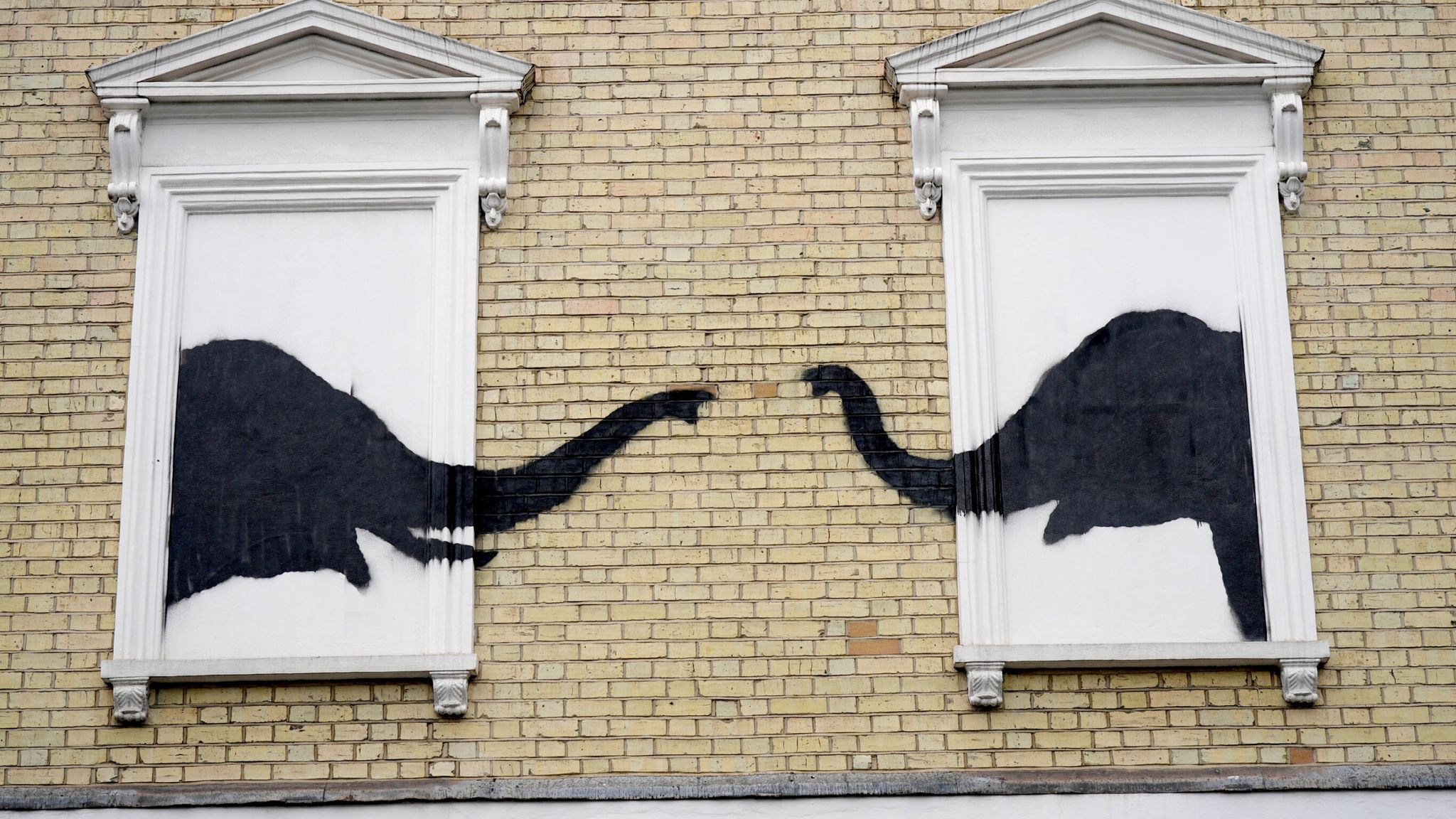 A new artwork depicting two elephants poking their heads out of blocked out windows unveiled by Banksy on the side of a building at the junction of Edith Grove and Edith Terrace, in Chelsea. Pic: PA