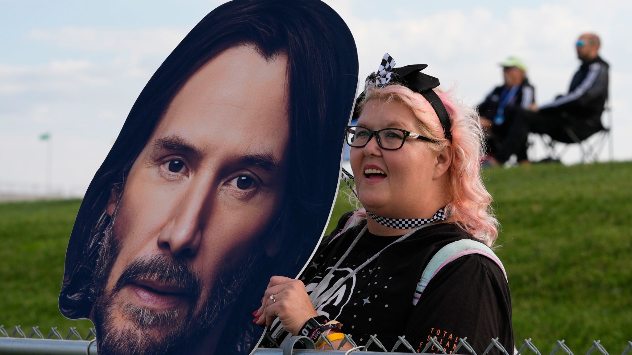 A fan holds a photo of Keanu Reeves as he drives during the GR Cup Series auto race at Indianapolis Motor Speedway, Saturday, Oct. 5, 2024, in Indianapolis. (AP Photo/Darron Cummings)